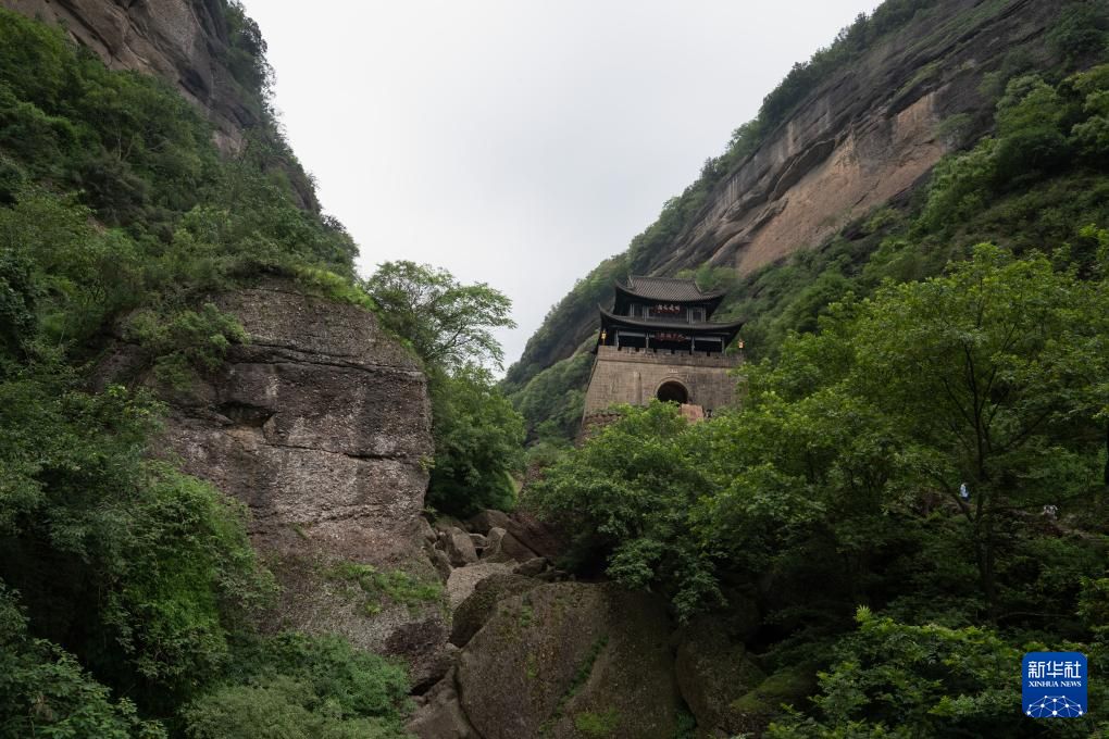 剑门关关楼立在两侧砂岩崖壁之间,山谷中可见巨石和树木